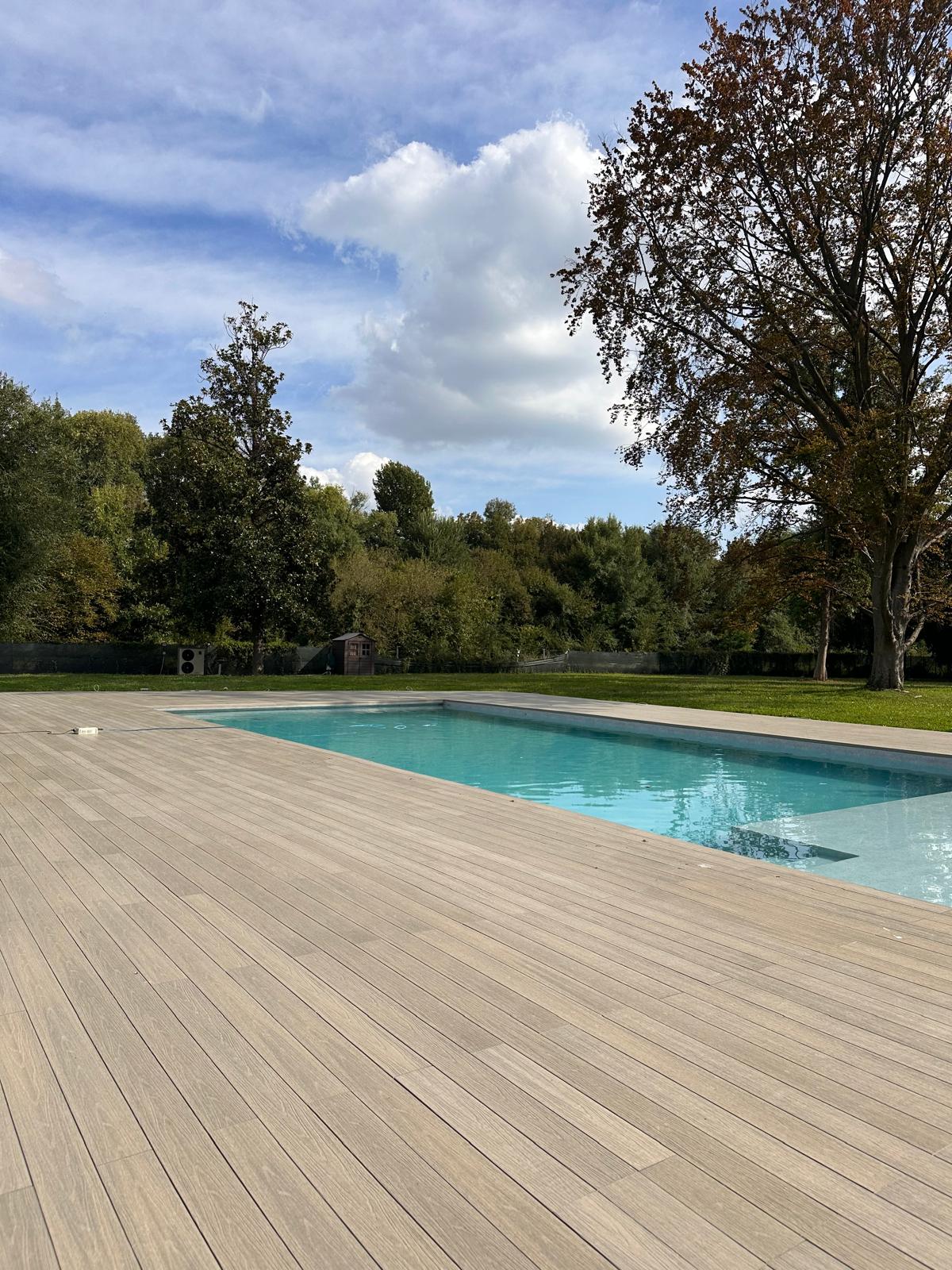 Doghe WPC color grigio chiaro posate a bordo piscina in una villa nel Padovano