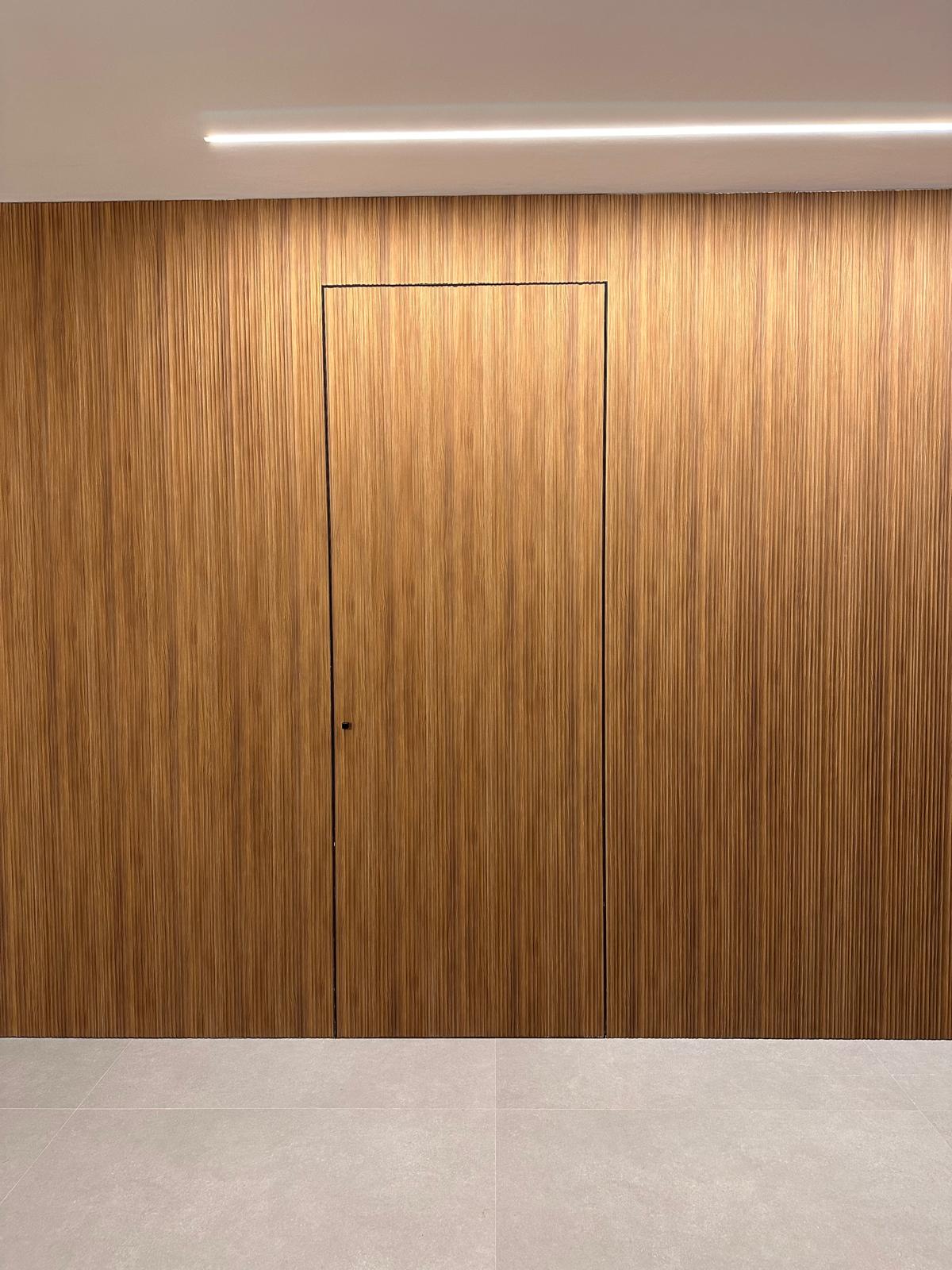 Porta filomuro allineata alla boiserie a listelli color teak in una casa a Cittadella