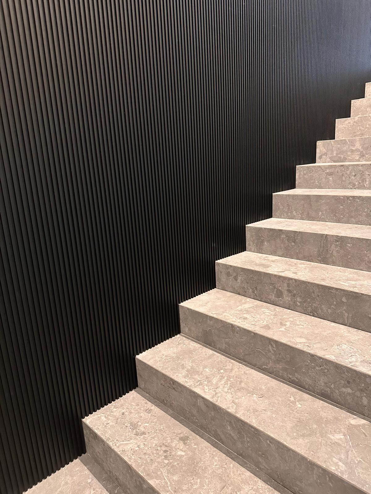Boiserie nera a listelli accanto alla scala in marmo chiaro a Rossano Veneto