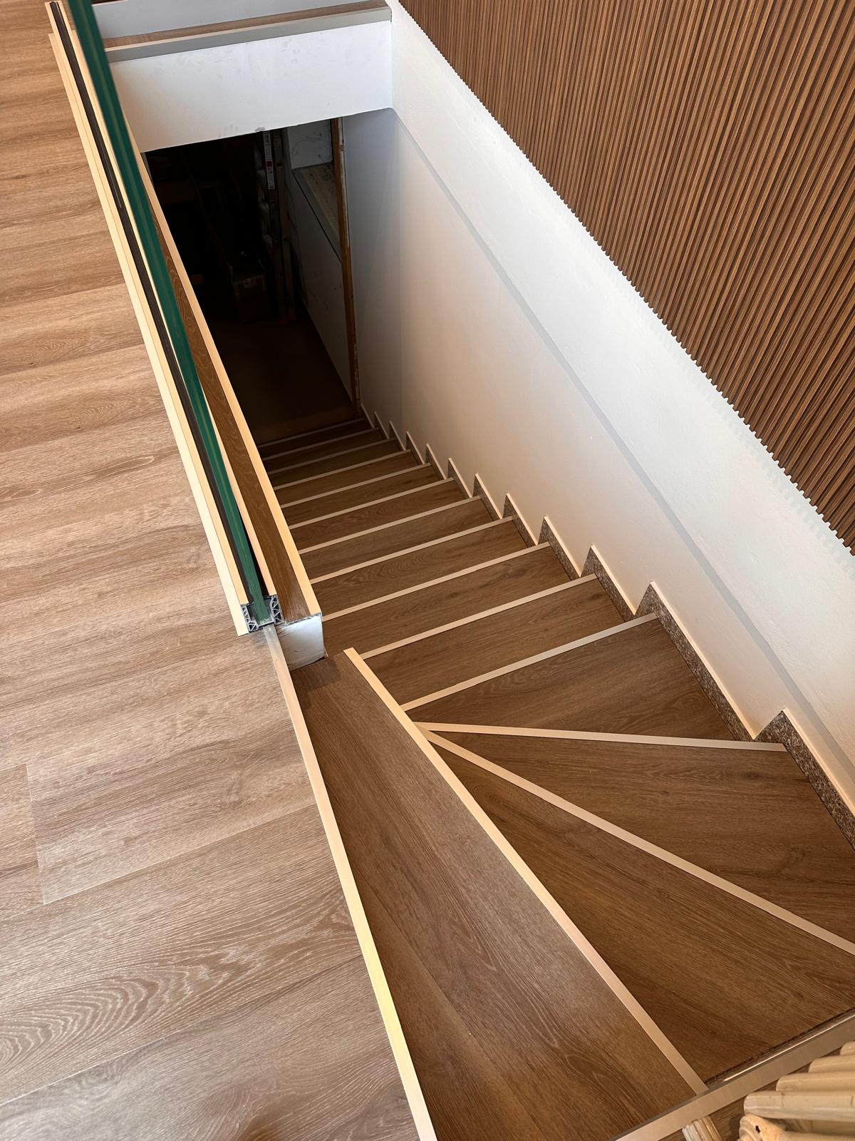 Scala con pavimento effetto legno, boiserie e parapetto in vetro a Mussolente